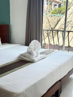 a white towel sitting on a bed with a window at La Xenia Hotel Kata Beach in Kata Beach