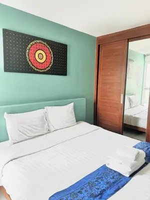 a bedroom with a large white bed and a mirror at La Xenia Hotel Kata Beach in Kata Beach