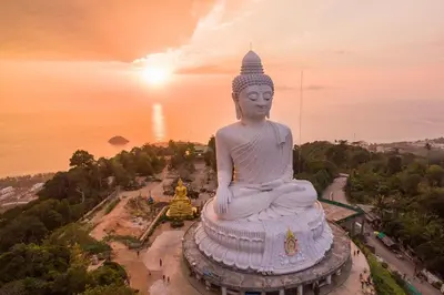 a large statue of aitating buddha at sunset at La Xenia Hotel Kata Beach in Kata Beach