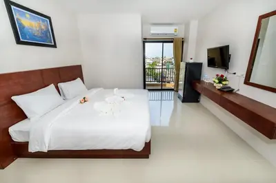 a bedroom with a large white bed and a television at The Topaz Residence Phuket Town in Phuket Town