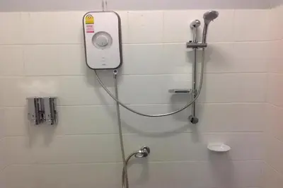 a shower in a bathroom with a hose on a wall at Beehive Phuket Old Town Hostel in Phuket Town