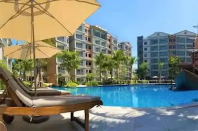 a pool with a chair and an umbrella and some buildings at Nayang Beach Brand New Executive Luxury Condo in Nai Yang Beach