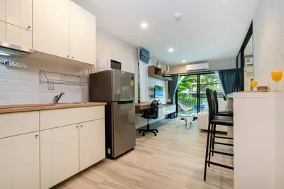a kitchen with a refrigerator and a table with chairs at Nayang Beach Brand New Executive Luxury Condo in Nai Yang Beach