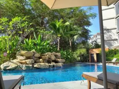 a swimming pool with a rock wall and an umbrella at Nayang Beach Brand New Executive Luxury Condo in Nai Yang Beach