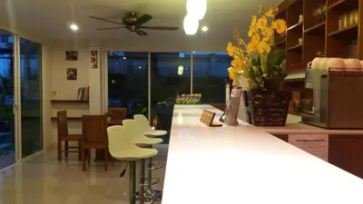 a kitchen with a counter with chairs and a vase of flowers at Green House Phuket in Ban Pa Khlok