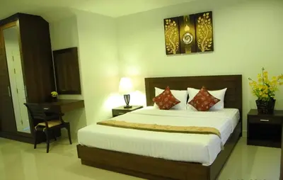 a hotel room with a bed and a desk and a bed at Green House Phuket in Ban Pa Khlok