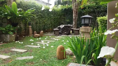 a garden with a statue in the middle of it at Green House Phuket in Ban Pa Khlok