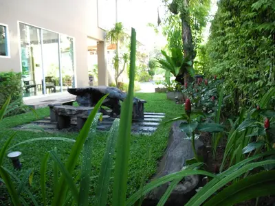 a garden with a bench in the middle of a yard at Green House Phuket in Ban Pa Khlok