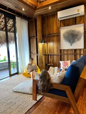 two people sitting on a couch in a living room at Sealord Naithon Beachfront Villa in Nai Thon Beach