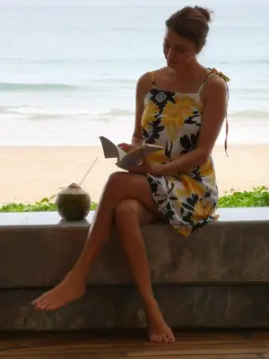 a woman sitting on a wall reading a book at Sealord Naithon Beachfront Villa in Nai Thon Beach