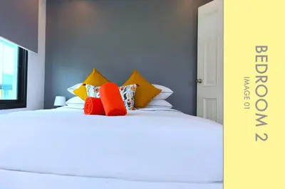 a bed with orange and yellow pillows on it at Tranquil Condo close to Beach in Kamala Beach