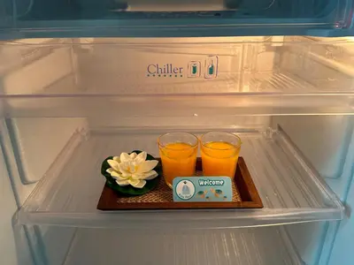 a refrigerator with two glasses of orange juice and a flower on a tray at Kata Place Hotel in Kata Beach