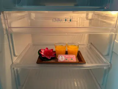a refrigerator with two glasses of orange juice and a flower at Kata Place Hotel in Kata Beach
