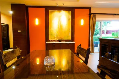 a dining room with a wooden table and orange walls at Luxurious large size swimming pool villa in Rawai in Ban Saiyuan (1)