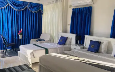 a bedroom with two beds and blue curtains at OASIS VILLA Karon Beach in Karon Beach