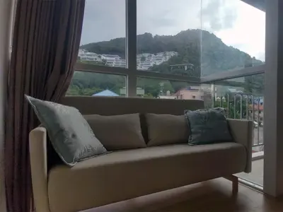 a couch in a room with a large window at Kata Beach OZONE Superb Fully Equipped studio kitchen washing machine air con in Kata Beach