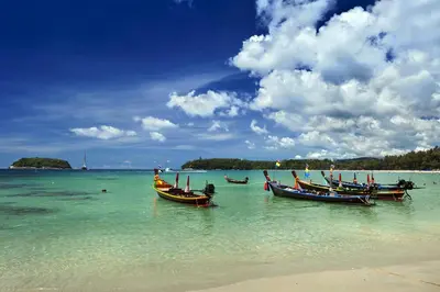 three boats sitting in the water on a beach at Kata Beach OZONE Superb Fully Equipped studio kitchen washing machine air con in Kata Beach