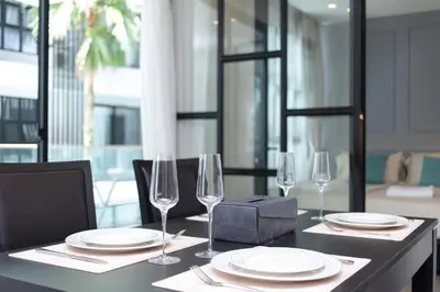 a table with plates and wine glasses on it at 2bdr Apartment near Surin beach PALM-C302 in Surin Beach