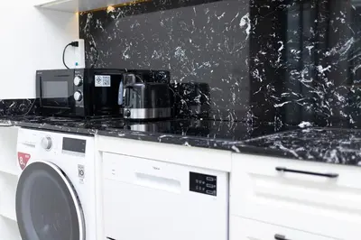 a black counter top with a microwave next to a washing machine at 2bdr Apartment near Surin beach PALM-C302 in Surin Beach
