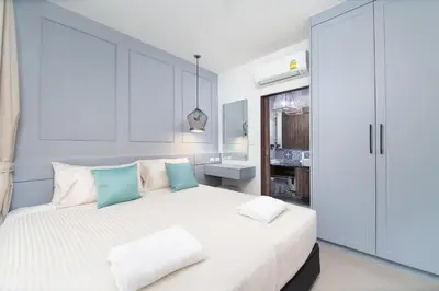 a white bedroom with a large white bed with blue pillows at 2bdr Apartment near Surin beach PALM-C302 in Surin Beach