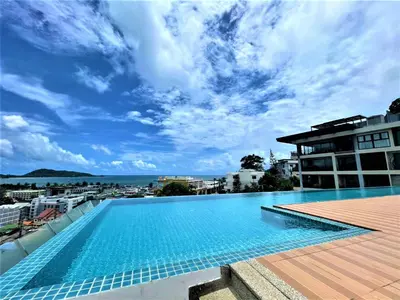 a swimming pool on the roof of a building with a blue sky at Patong - The Unity Seaview & Mountain Residence in Patong Beach