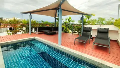 a pool on a deck with two chairs and an umbrella at Casuarina Shores Apartment - SHA Plus in Bang Tao Beach