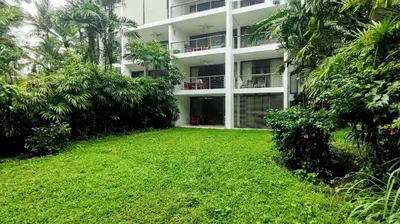 an apartment building with a lawn in front of it at Casuarina Shores Apartment - SHA Plus in Bang Tao Beach