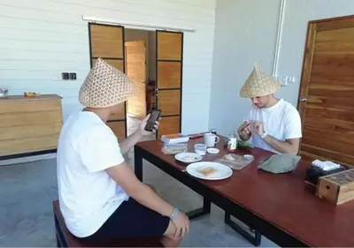two people sitting at a table with hats on their heads at Farm House kohyaoyai in Ko Yao Yai