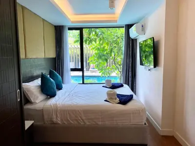 a bedroom with a bed with a large window at The aristo-access pool room Surin beach in Phuket Town