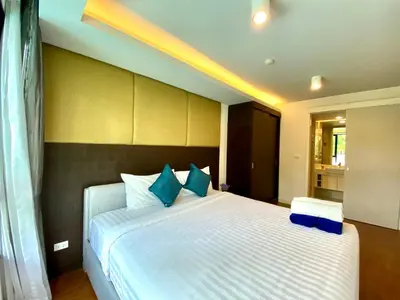 a bedroom with a large white bed with blue pillows at The aristo-access pool room Surin beach in Phuket Town