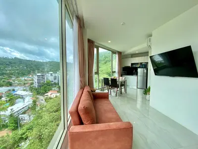 a living room with a couch and a large window at Oceana Sea View - Kamala Beach in Kamala Beach