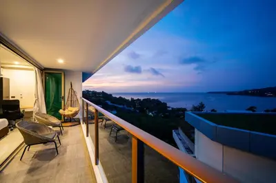 a balcony with a view of the ocean at night at Oceana Sea View - Kamala Beach in Kamala Beach
