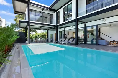 a house with a swimming pool in front of a house at Loft Style 4BR Villa Sunset Garden 4 with 12m Salt Water Pool, near NaiHarn in Rawai Beach