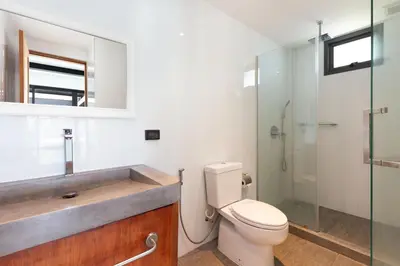 a bathroom with a toilet and a glass shower at Loft Style 4BR Villa Sunset Garden 4 with 12m Salt Water Pool, near NaiHarn in Rawai Beach