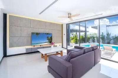 a living room with a couch and a tv at Loft Style 4BR Villa Sunset Garden 4 with 12m Salt Water Pool, near NaiHarn in Rawai Beach