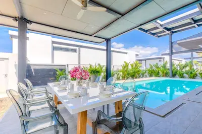 a dining table and chairs in a patio with a pool at Loft-Style Hyper Modern 4Br Villa Sunset garden 6 with 12x5m Salt Pool in Rawai Beach