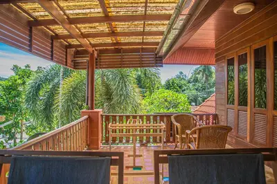 a porch of a house with chairs and a table at Kata Pool Villa ​No.7 in Kata Beach