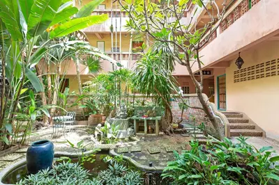 a courtyard in a building with a pond and trees at Casa Brazil Homestay in Karon Beach