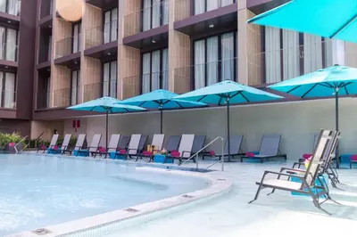 a swimming pool with chairs and umbrellas and a building at GLOW Mira Karon Beach in Karon Beach