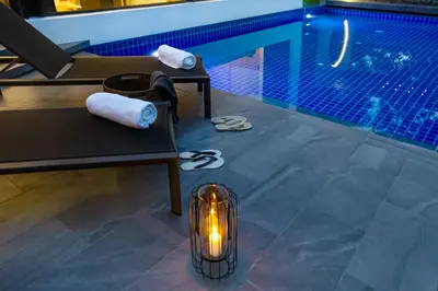 a lantern sitting next to a swimming pool with a candle at Villoft Zen Living Resort in Thalang