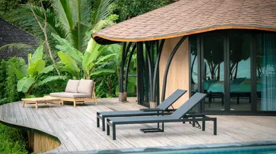 a deck with two lounge chairs and a pool at Touch Beachfront Pool Villa Koh Yao Noi in Ko Yao Noi