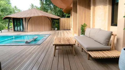 a deck with a chair and a table next to a pool at Touch Beachfront Pool Villa Koh Yao Noi in Ko Yao Noi