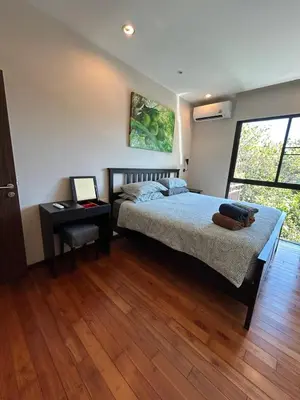a bedroom with a bed and a table with a laptop at The Title Rawai Beach West Wing by EHM in Rawai Beach