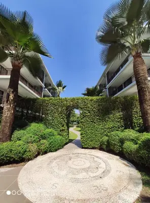 a garden with palm trees in front of a building at The Title Rawai Beach West Wing by EHM in Rawai Beach
