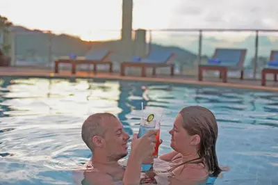 a man and woman in a swimming pool holding a cell phone at Add Plus Hotel & SPA in Patong Beach