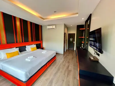 a bedroom with a large bed and a flat screen tv at WOW PHUKET in Phuket Town