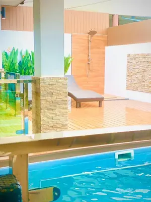 a swimming pool with a chair next to the water at The Chic Pool Villa in Nai Yang Beach