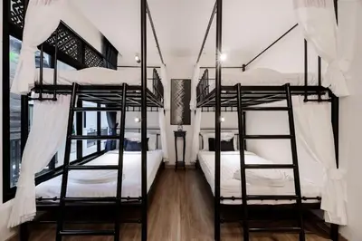 a bedroom with three bunk beds with white sheets at Sabai Hotel Aonang in Ao Nang Beach