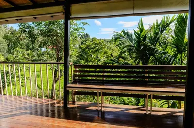 a wooden porch with a bench on a balcony at Kunna House in Ko Yao Noi