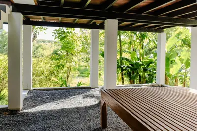 a wooden bench on a porch with a view at Kunna House in Ko Yao Noi